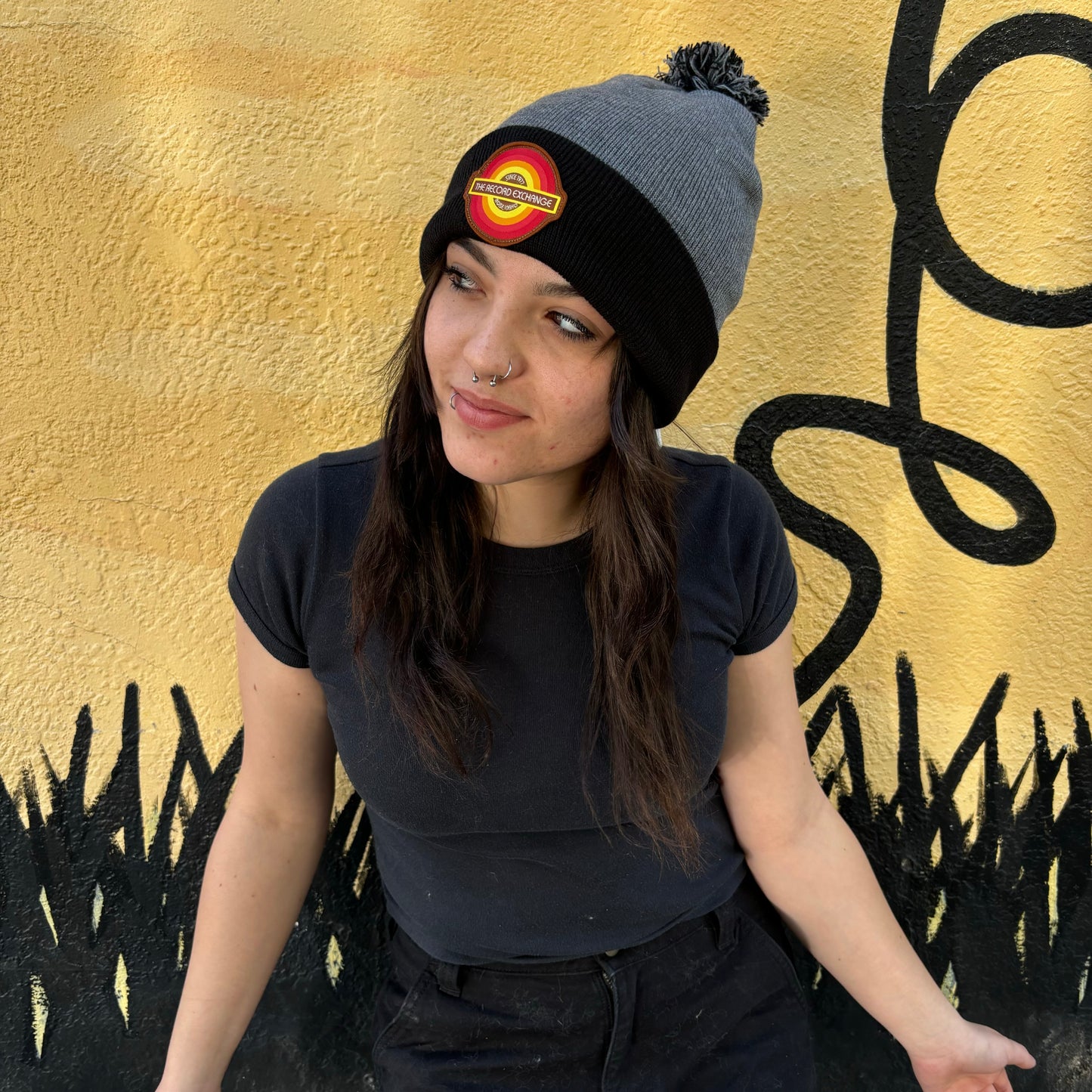 Model showing off Fuzzy Warm Grey and Black Beanie with The Record Exchange logo.